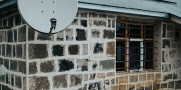 Stone exterior house with solar panel and satellite dish, showcasing sustainable energy solutions.