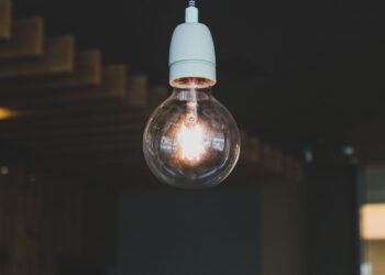 Artistic close-up of an illuminated hanging light bulb indoors, evoking warmth and creativity.