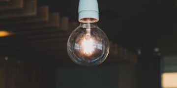 Artistic close-up of an illuminated hanging light bulb indoors, evoking warmth and creativity.