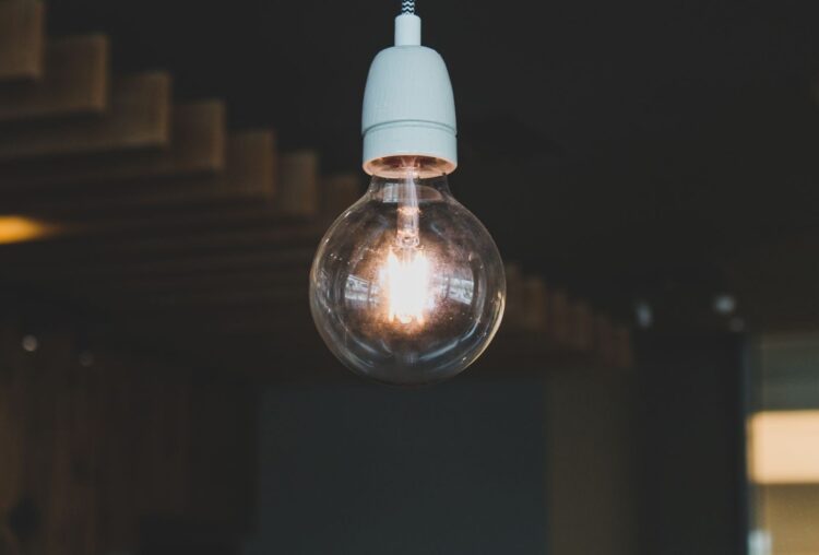 Artistic close-up of an illuminated hanging light bulb indoors, evoking warmth and creativity.