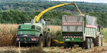 Agricultural machinery harvesting corn in rural countryside near Hamburg, Germany.