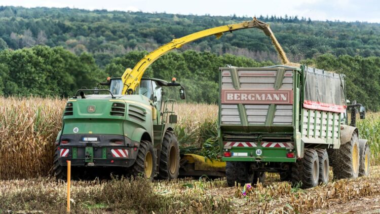 Agricultural machinery harvesting corn in rural countryside near Hamburg, Germany.