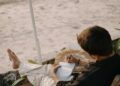Man relaxing and writing in a journal on a serene beach in Goa, India.