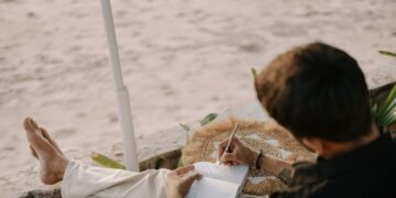 Man relaxing and writing in a journal on a serene beach in Goa, India.