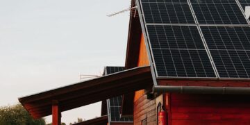 Wooden house featuring solar panels, captured at sunset, highlighting eco-friendly architecture.