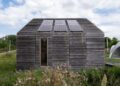 Sustainable wooden house with solar panels and lush surroundings.