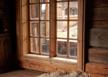 Warm rustic setting in a Norwegian log cabin, featuring a wooden window and sheepskin decor.