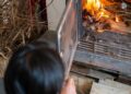 A person tends to a wood-burning fireplace, creating a warm indoor atmosphere.
