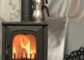 Warm indoor setting with a metal kettle on a burning wood stove, perfect for comfort theme.