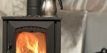 Warm indoor setting with a metal kettle on a burning wood stove, perfect for comfort theme.