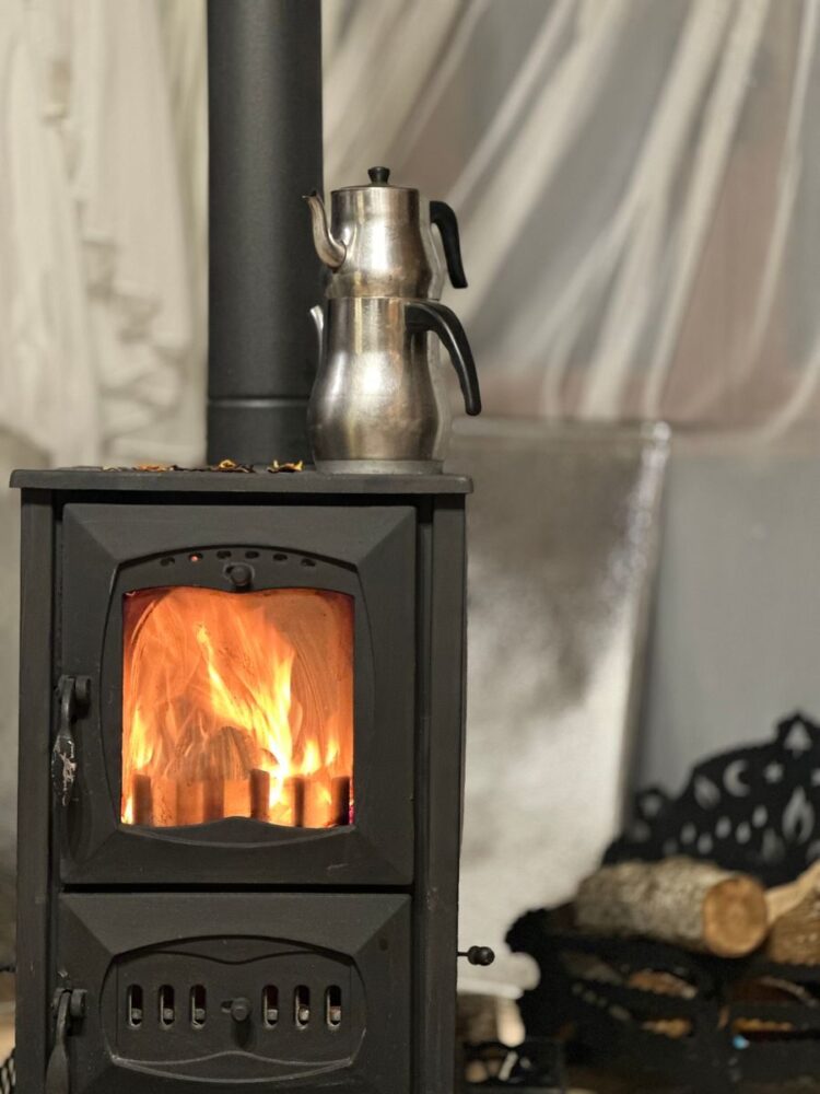 Warm indoor setting with a metal kettle on a burning wood stove, perfect for comfort theme.