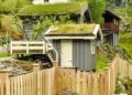 Picturesque view of traditional green-roofed houses surrounded by lush greenery and wooden fencing.