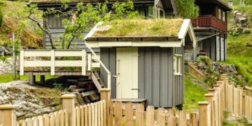 Picturesque view of traditional green-roofed houses surrounded by lush greenery and wooden fencing.