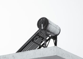 A minimalist view of an urban rooftop featuring a solar water heater against a clear sky.