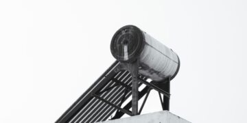 A minimalist view of an urban rooftop featuring a solar water heater against a clear sky.